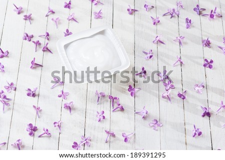 cosmetic cream with flowers on white wood table