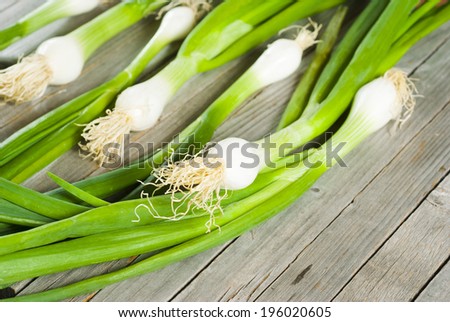 fresh spring onions with root on old wooden table