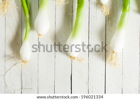 fresh spring onions with root on wooden table