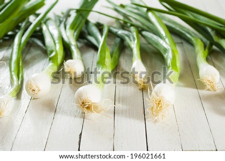 fresh spring onions with root on wooden table
