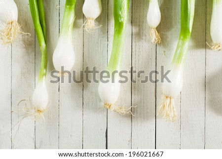 fresh spring onions in a row on white wooden table