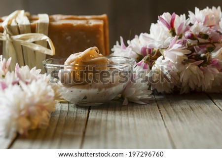 cosmetic cream, soap blocks and flowers on old wood background