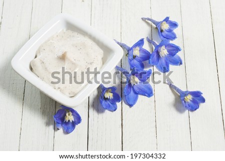 face cream and flowers on white wooden background