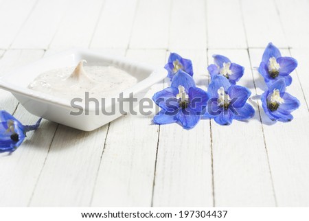 face cream and flowers on white wooden background