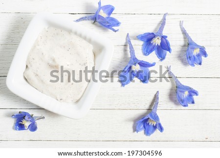 face cream and flowers on white wooden background directly above