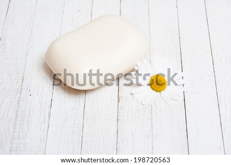 bar of soap with chamomile flower on white wood table