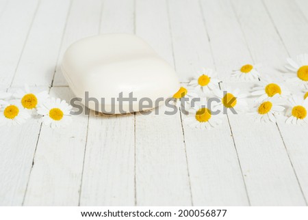 soap bar with chamomile flowers on white wood surface