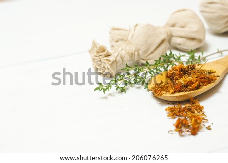 moisturizer with dried St. John\'s Wort on wooden spoon and floating flowers