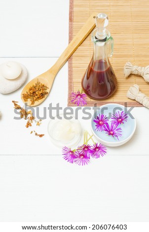 moisturizer with dried St. John\'s Wort on wooden spoon and floating flowers