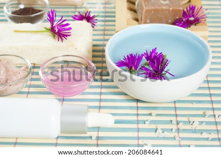 spa setting with lavender cream, bath salt and floating flowers on bamboo