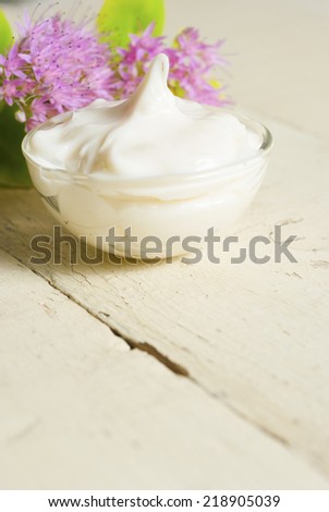 white face cream and pink flowers on bright, rusty wood