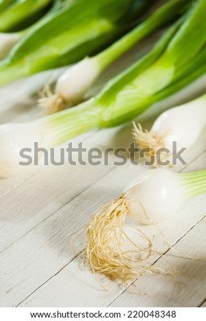 fresh spring onions with root on white wooden