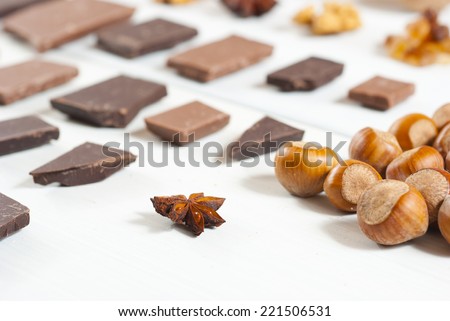 dessert ingredients and chocolate blocks in a row on white wooden table background