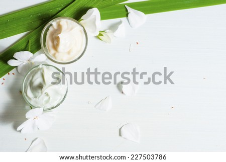 hand cream and face cream with white flowers on bright wooden table
