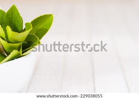 herbal leaves in china bowl on white wood table