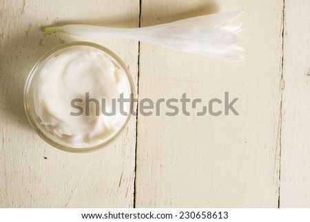 facial cleanser cream with white flower on rusty wooden table