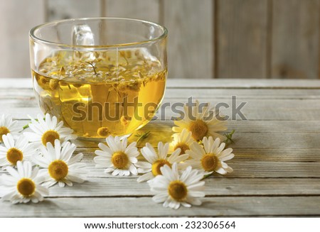 herbal tea with chamomile flowers, old wood table background