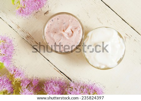 hand and face cream with pink flowers on bright, rusty wooden