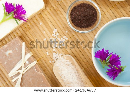 spa setting with bath salt and floating flowers on bamboo