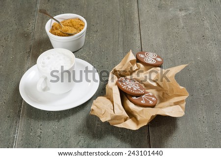 milk coffee with paper wrapped gingerbread cakes and brown sugar on rusty wooden
