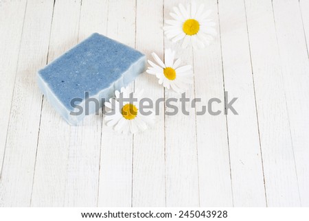 soap with herbal flowers on white wood table
