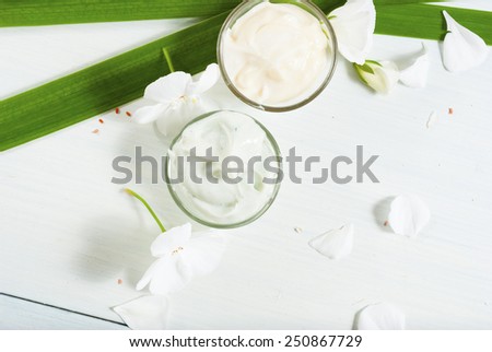hand cream and face cream with white flowers on bright wooden table