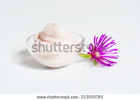 cosmetic cream with purple flowers on white wood table