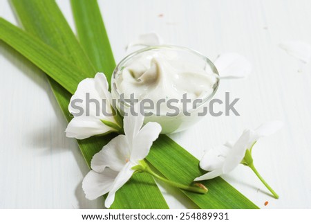 cosmetic cream with white flowers on bright wooden table