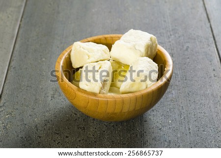 shea butter in bamboo bowl, dark wood table background
