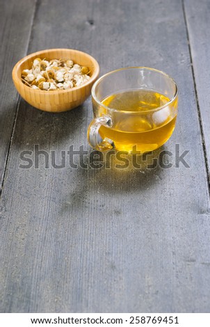 cup of chamomile tea with dried flowers on black wood table