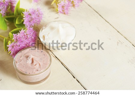 hand and face cream with stone crop on bright, rusty wooden