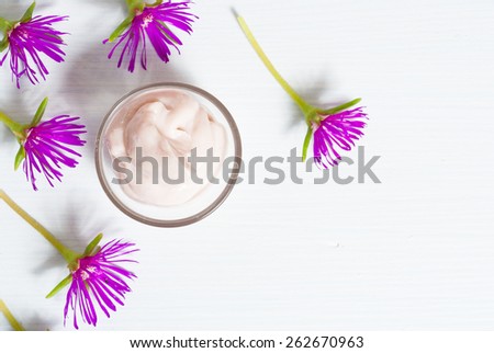cosmetic cream with purple flowers on white wood table