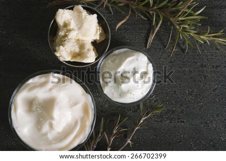natural moisturizers and raw shea butter in alloy bowl on black wooden table