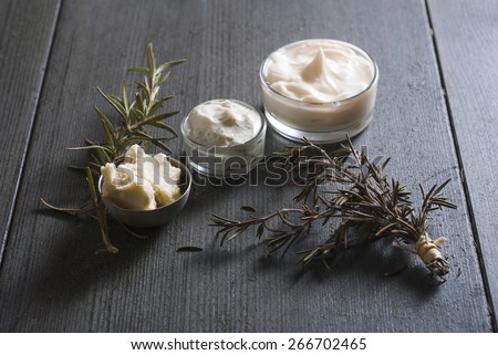 natural moisturizers and raw shea butter in alloy bowl on black wooden table