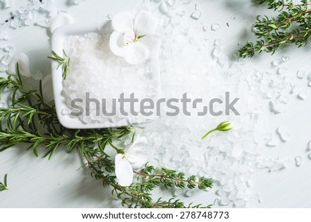 salt with flowers, rosemary and savory twigs on white wood table