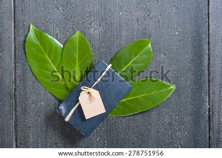charcoal soap and herbal leaves on black wooden