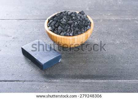 block of natural carbon soap and a pile of coal on black wood table background