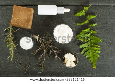 moisturizer, pipette, organic soap, shea butter on black wooden table