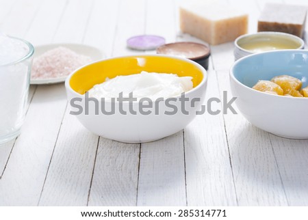 different bath salts, bees wax , makeup base,  soaps and cosmetic creams on white wooden background