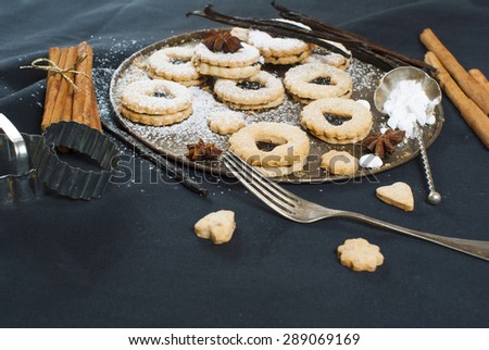 linzer cookies with vanilla beans and cinnamon sticks on black canvas background