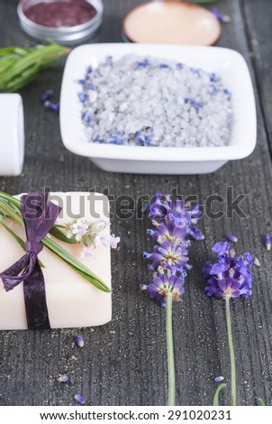 different cosmetic creams, bath salt, soap with fresh lavender flowers on black wooden texture