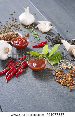 fresh and dried chili fruits, peppercorn, sauce and garlic, bay leaves on old black wooden table background