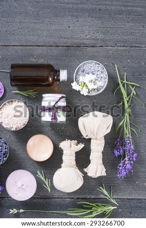 beauty product samples with lavenders, bath salts and massage pouches on dark wood table background