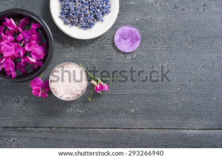 pink linaria flowers and bath salt, dried lavender buds on black wood table