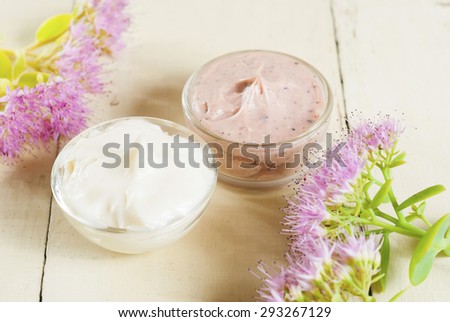 hand and face cream with pink flowers on bright, rusty wooden