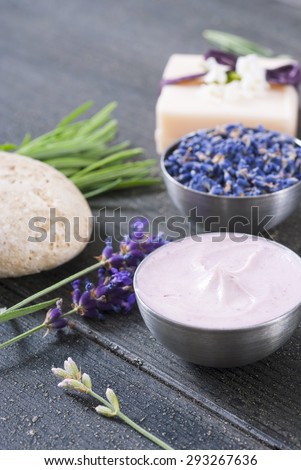 beauty product samples with lavender flowers on black wood table background