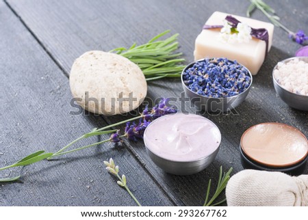 beauty product samples with fresh purple and blue dried lavenders, bath salts on dark wood table background