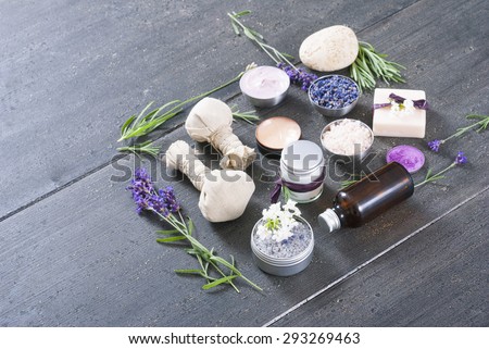 beauty product samples with fresh purple and blue dried lavenders, bath salts and massage pouches on dark wood table background