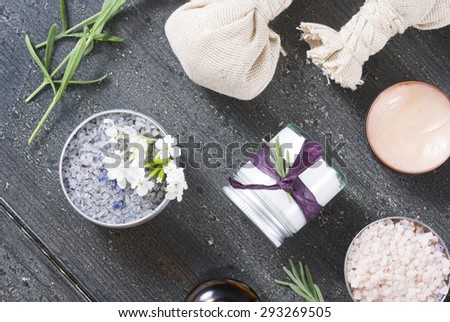 beauty product samples with fresh purple and blue dried lavenders, bath salts and massage pouches on dark wood table background