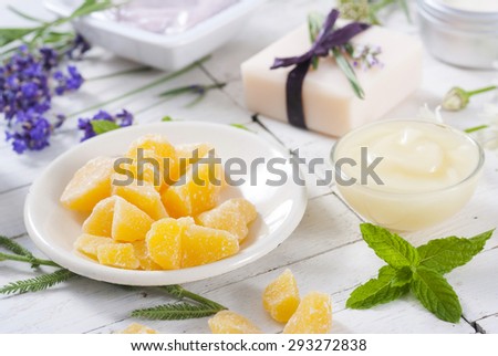 cosmetic creams, lip balm, soap and bath salt with herbal flowers on white wooden table